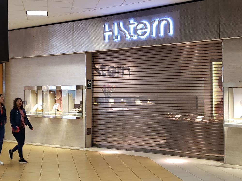 Puerta enrollable metálica Full Vision en tienda de joyería dentro de centro comercial, con alta transparencia que realza la exhibición y mantiene la seguridad.
