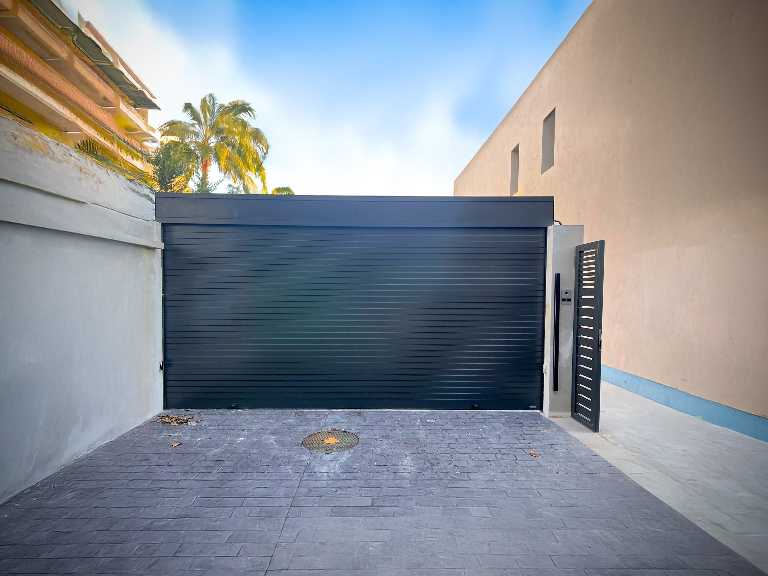 Puerta enrollable de aluminio Aluroll en color negro, instalada en entorno comercial urbano, con diseño moderno, acabado uniforme y alta durabilidad.
