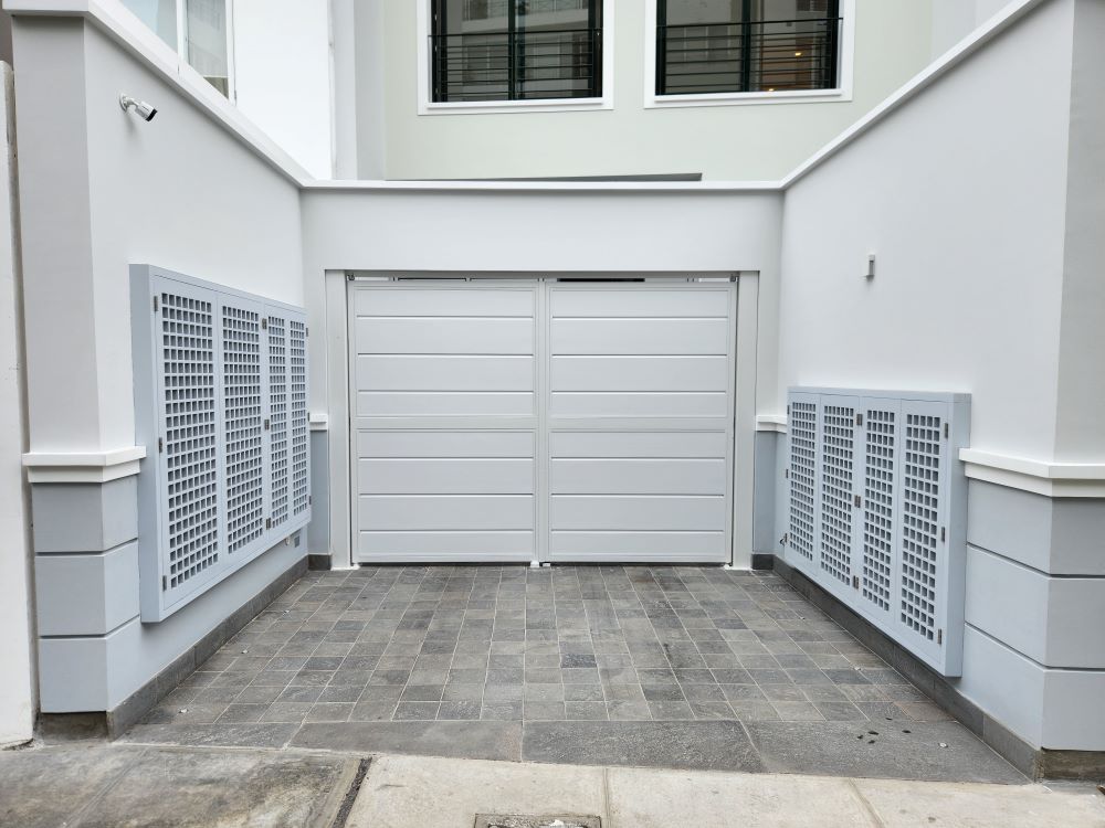 Puerta batiente de garaje en color blanco instalada en vivienda, construida con estructura de acero galvanizado que garantiza resistencia, seguridad y desempeño confiable para uso vehicular.