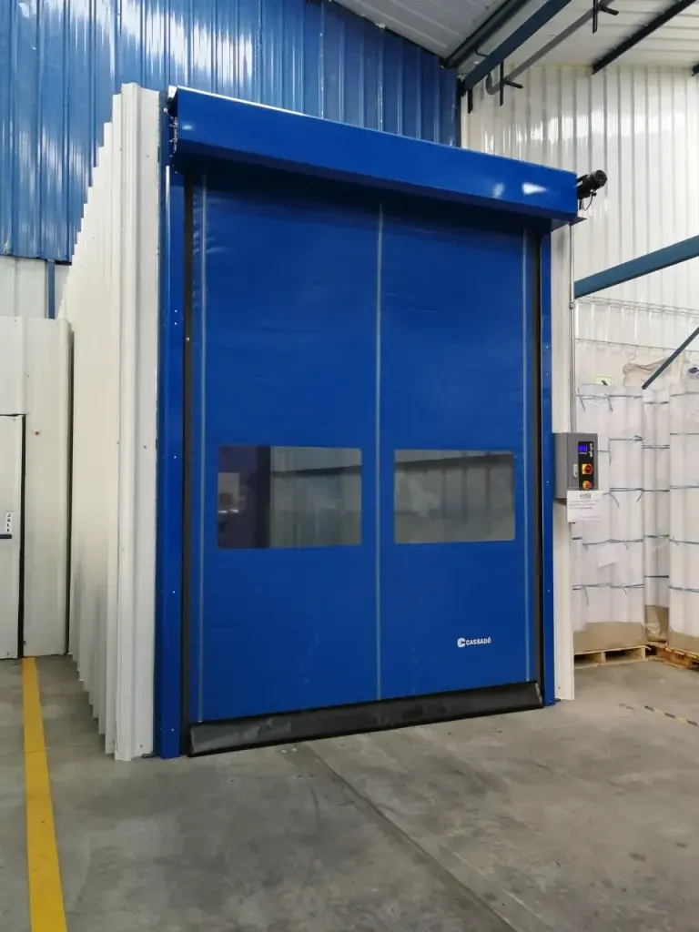 Puerta rápida de PVC FastZipp autoreparable en color azul, instalada en entorno logístico, con sistema que recupera el paño tras impactos y mantiene la continuidad operativa.