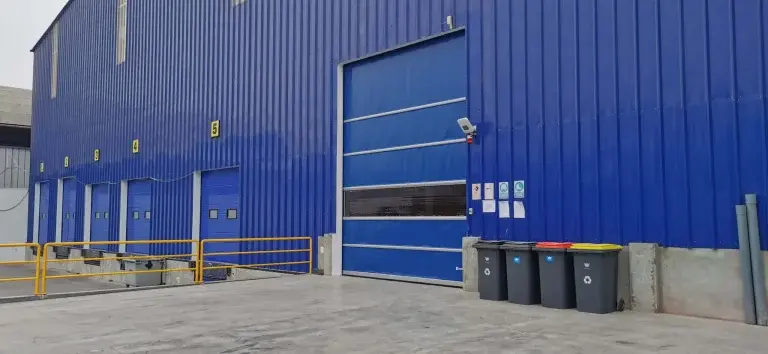 Puerta rápida de PVC FastMax en color azul instalada en exteriores, con apertura vertical que mejora el control entre ambientes y reduce la variación de temperatura.