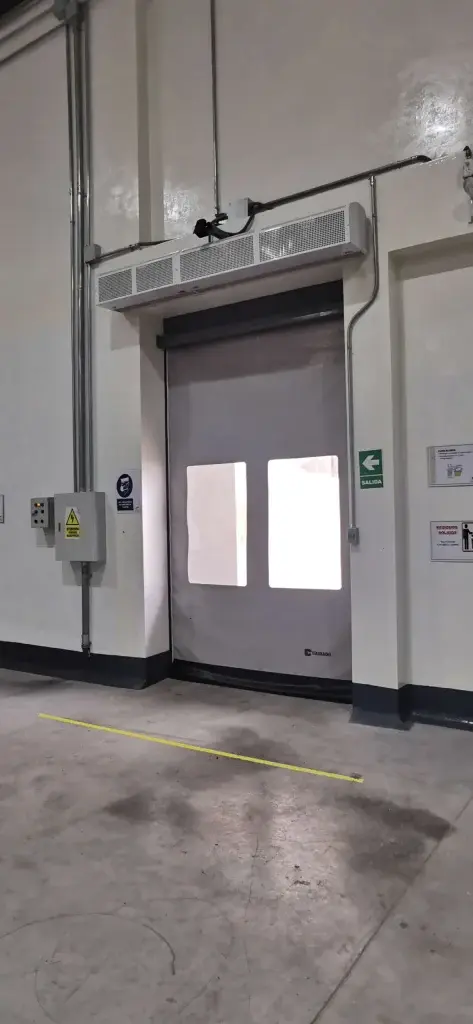 Puerta rápida de PVC FastZipp autoreparable en color blanco, instalada en zona logística, con sistema que se reintegra tras impactos y reduce tiempos de paradas.