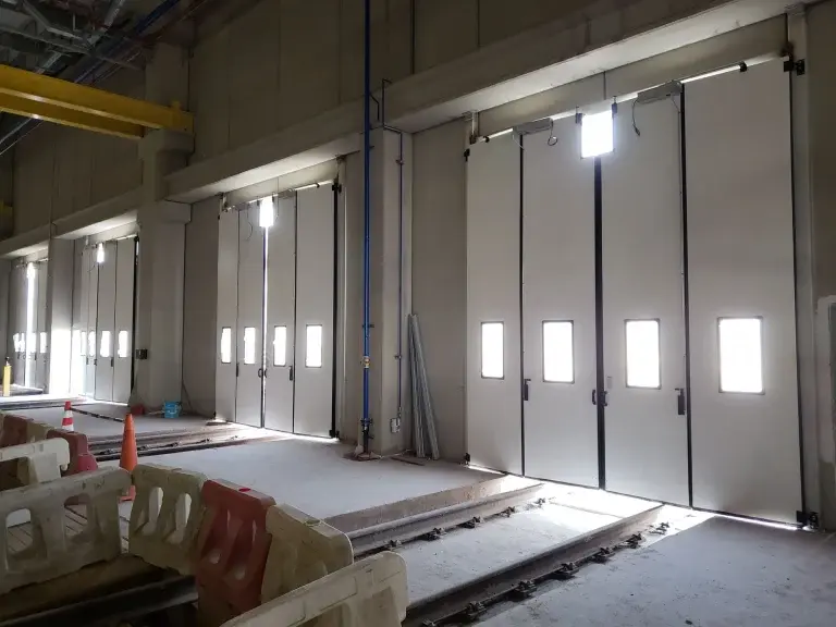 Puertas abatibles industriales instaladas en entorno industrial, con apertura lateral y paneles insulados articulados que aportan robustez, estabilidad y facilidad de operación.