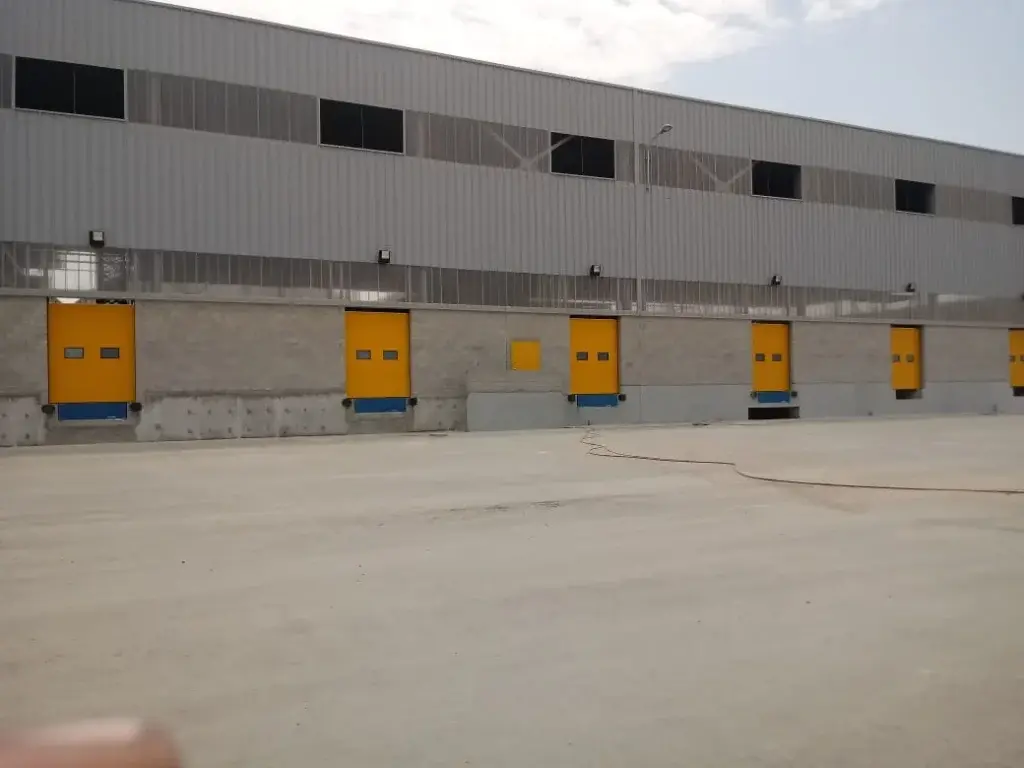Puertas seccionales industriales de color amarilo, en operación dentro de plataforma logística, con paneles seccionados que permiten un cierre seguro y eficiente en zonas de carga y descarga.