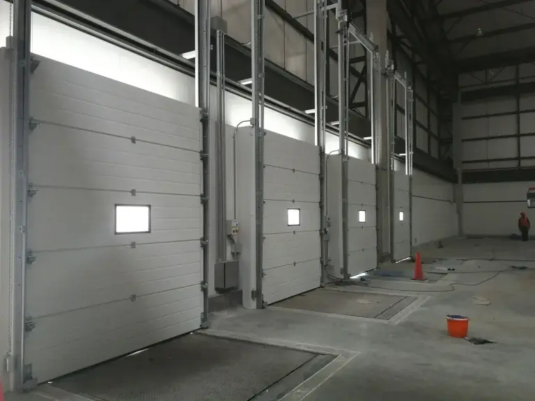 Puertas seccionales industriales instaladas en centro de distribución, con sistema de paneles articulados que aseguran un cierre confiable en andenes de carga y áreas logísticas.
