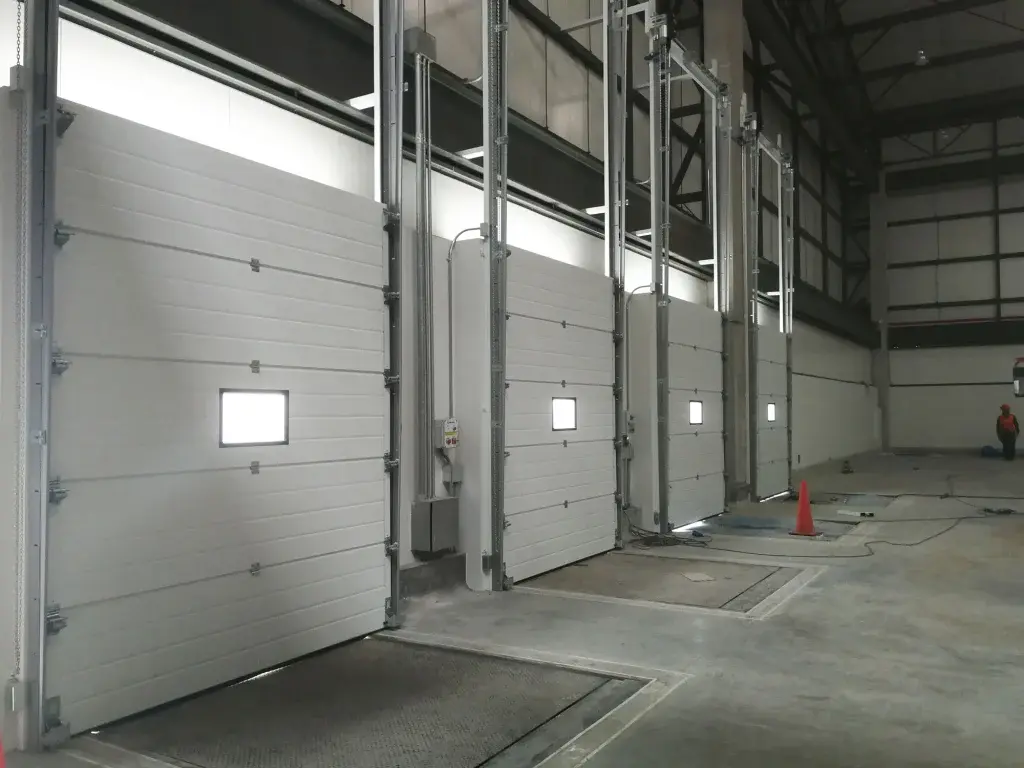 Puertas seccionales industriales instaladas en almacén, con sistema de apertura vertical y diseño modular que asegura un cierre confiable en operaciones logísticas.