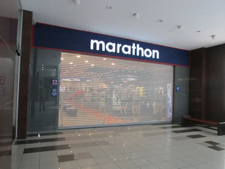 Puerta enrollable metálica Full Vision en tienda retail (Marathon)de centro comercial, con diseño microperforado que brinda visibilidad y seguridad.